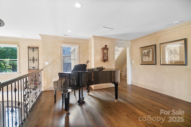 living area with crown molding, visible vents, baseboards, and wood finished floors