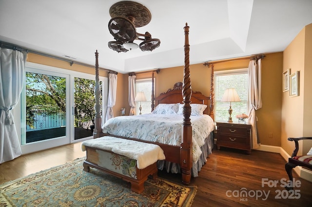 bedroom featuring baseboards, visible vents, a tray ceiling, access to exterior, and wood finished floors