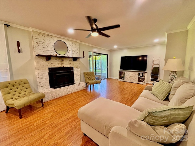 living room featuring ceiling fan, a fireplace, ornamental molding, wood finished floors, and baseboards