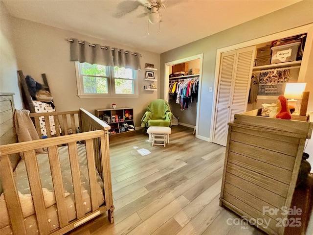 bedroom with ceiling fan, baseboards, multiple closets, and wood finished floors