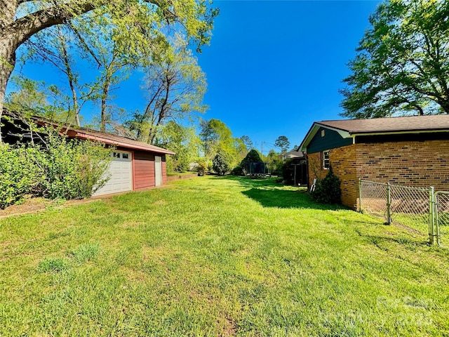 view of yard featuring a garage, fence, and an outdoor structure