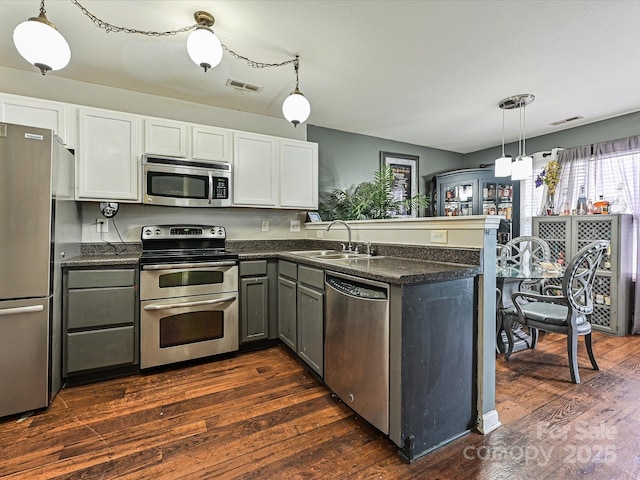 kitchen with visible vents, a sink, dark countertops, a peninsula, and stainless steel appliances