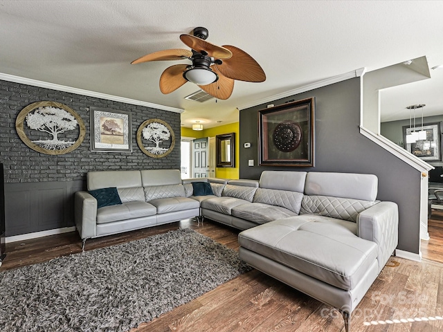 living area featuring visible vents, ornamental molding, a ceiling fan, and wood finished floors