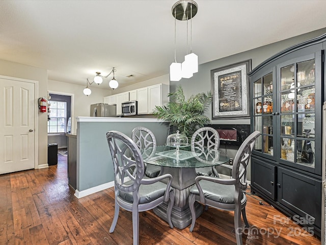 dining area featuring dark wood-type flooring and baseboards