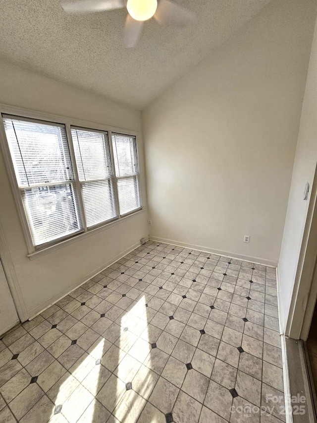 unfurnished room with ceiling fan, a textured ceiling, baseboards, and lofted ceiling
