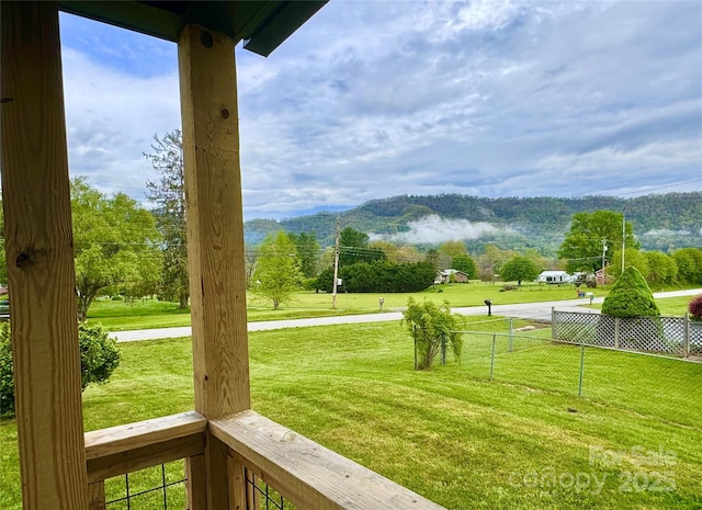 surrounding community with fence, a yard, and a mountain view