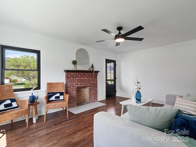 living room with dark wood-type flooring, a wealth of natural light, ceiling fan, and a fireplace