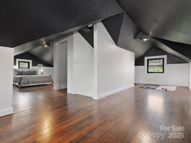 additional living space featuring hardwood / wood-style floors, vaulted ceiling, and baseboards