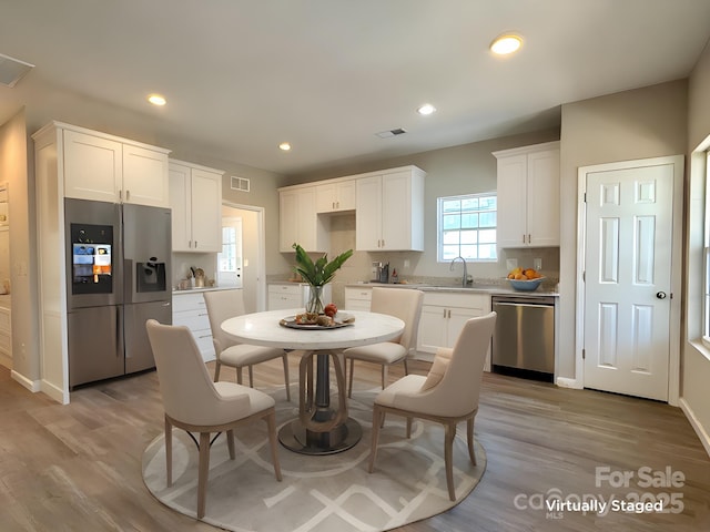 kitchen with a sink, white cabinets, light wood-style floors, and stainless steel appliances