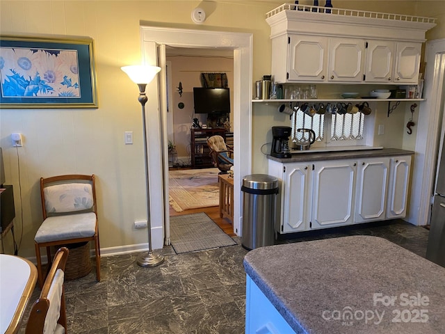 kitchen with dark countertops, open shelves, white cabinetry, and marble finish floor