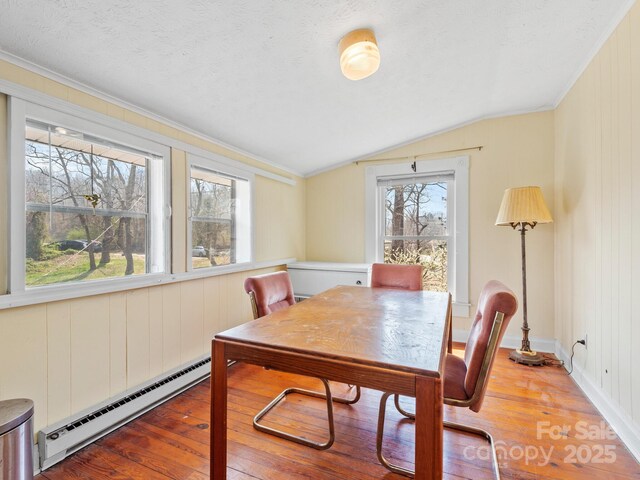 dining space featuring a baseboard radiator, a textured ceiling, lofted ceiling, and hardwood / wood-style flooring