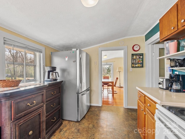 kitchen with crown molding, freestanding refrigerator, lofted ceiling, and a textured ceiling
