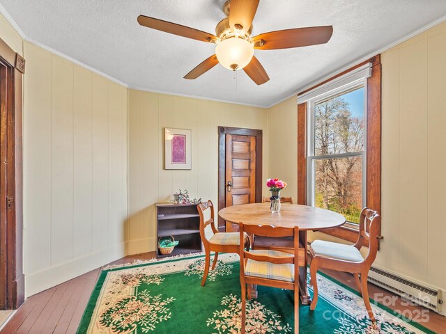 dining area with a baseboard radiator, ceiling fan, hardwood / wood-style floors, and a textured ceiling