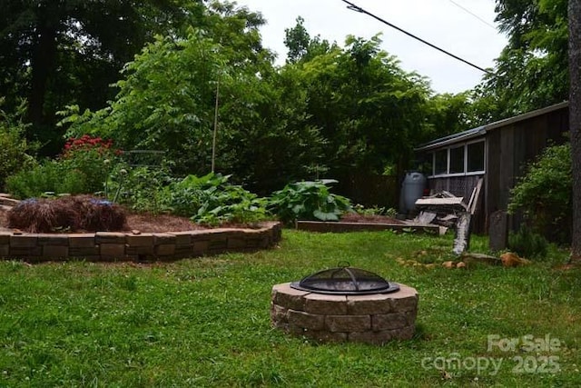 view of yard with a garden and an outdoor fire pit