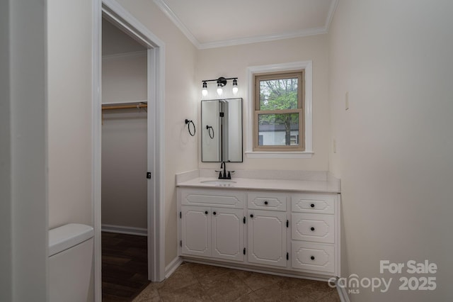 bathroom featuring vanity, baseboards, ornamental molding, tile patterned floors, and toilet