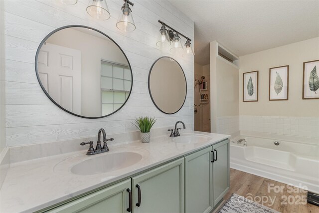 full bath with a garden tub, wood finished floors, a sink, and double vanity