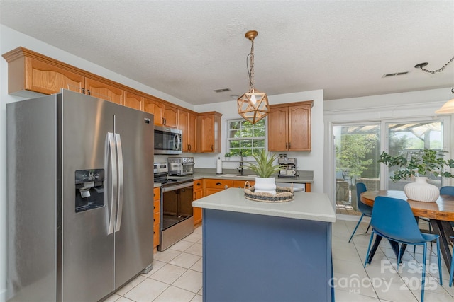 kitchen featuring stainless steel appliances, light countertops, visible vents, and hanging light fixtures