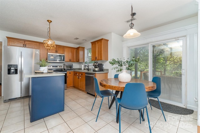 kitchen featuring pendant lighting, a center island, stainless steel appliances, and light countertops