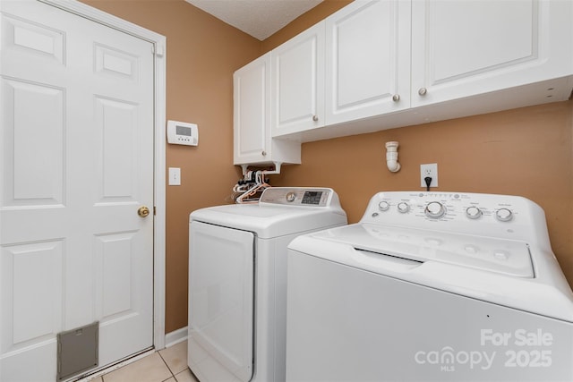 laundry room with cabinet space, baseboards, light tile patterned floors, and washer and clothes dryer