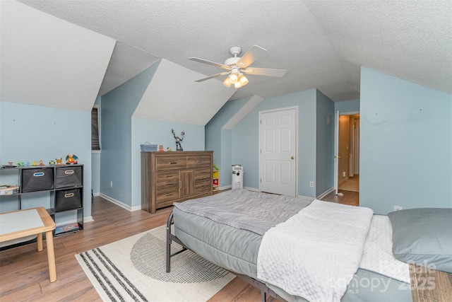 bedroom featuring ceiling fan, vaulted ceiling, baseboards, and light wood-type flooring
