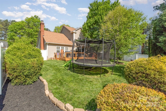 view of yard featuring fence, a wooden deck, and a trampoline