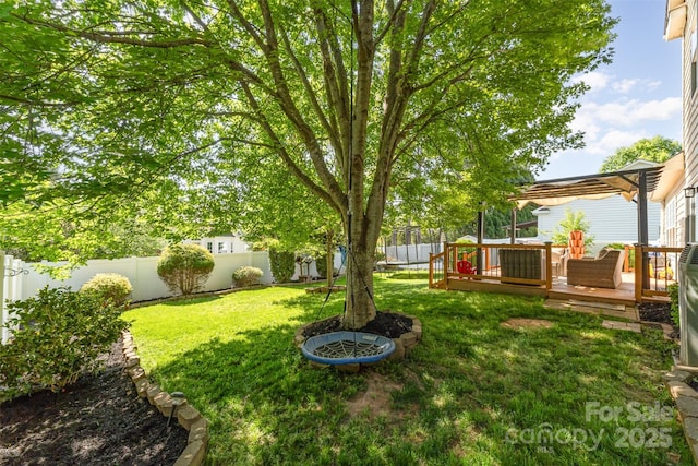view of yard featuring a trampoline, a fenced backyard, and a deck