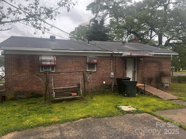 back of property with a yard and brick siding