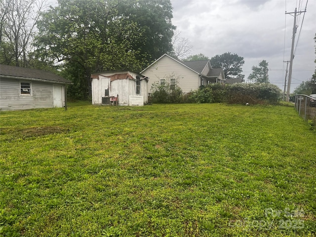 view of yard with an outdoor structure, fence, and a storage unit