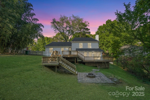 rear view of house with a yard, an outdoor fire pit, a wooden deck, and a chimney