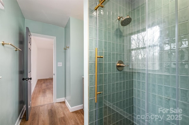 bathroom with baseboards, a shower stall, and wood finished floors