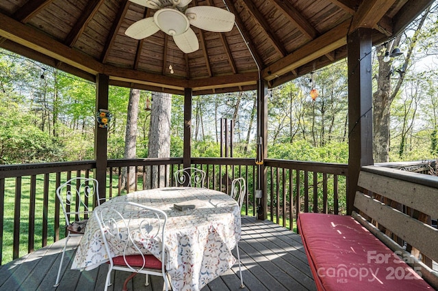wooden terrace with a gazebo, outdoor dining area, and ceiling fan
