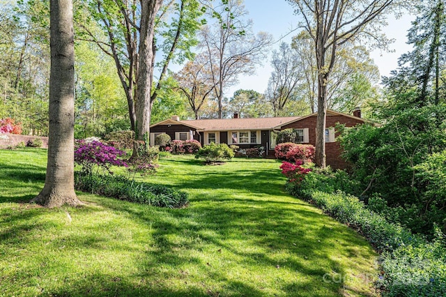 view of front of property with brick siding, a chimney, and a front lawn