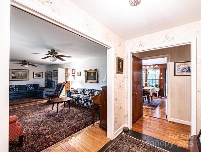 living area with baseboards, ceiling fan, and hardwood / wood-style floors