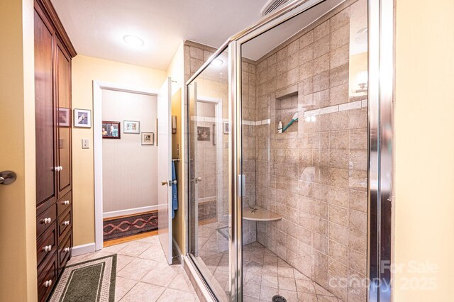 full bath with tile patterned flooring, baseboards, and a shower stall