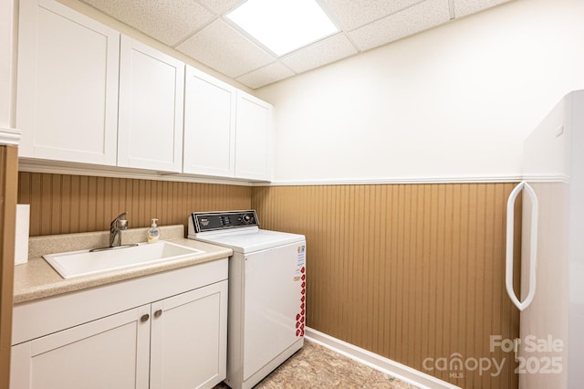 washroom with cabinet space, washer / dryer, wainscoting, and a sink