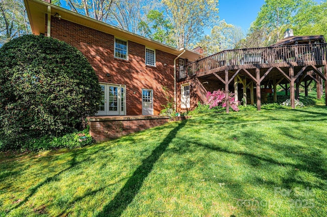 rear view of house with brick siding, a lawn, a chimney, and a deck