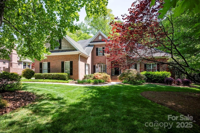 view of front of home with brick siding, a standing seam roof, and a front lawn