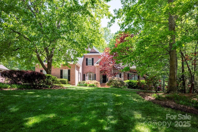 obstructed view of property with a front yard and brick siding