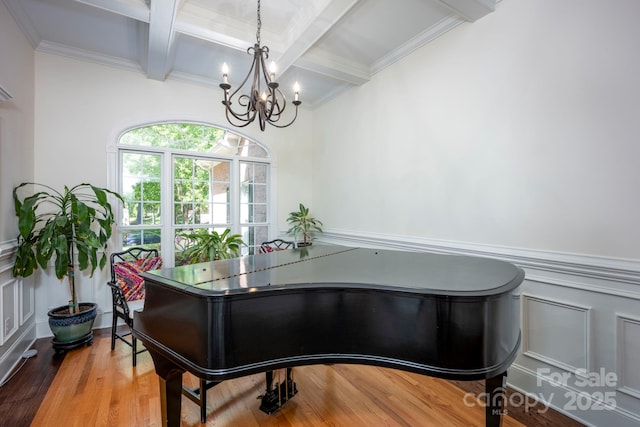 office area featuring an inviting chandelier, beam ceiling, coffered ceiling, a decorative wall, and wainscoting