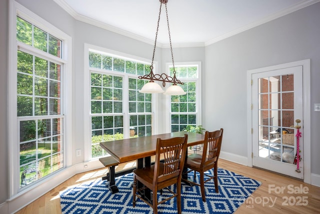 dining room with baseboards, ornamental molding, and light wood finished floors