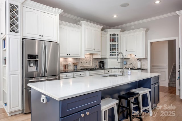 kitchen featuring stainless steel refrigerator with ice dispenser, white cabinetry, blue cabinetry, and a sink