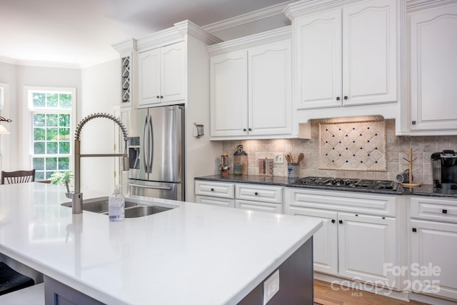 kitchen with tasteful backsplash, white cabinets, stainless steel appliances, and a sink