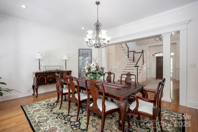 dining area with stairway, wood finished floors, a notable chandelier, and ornamental molding