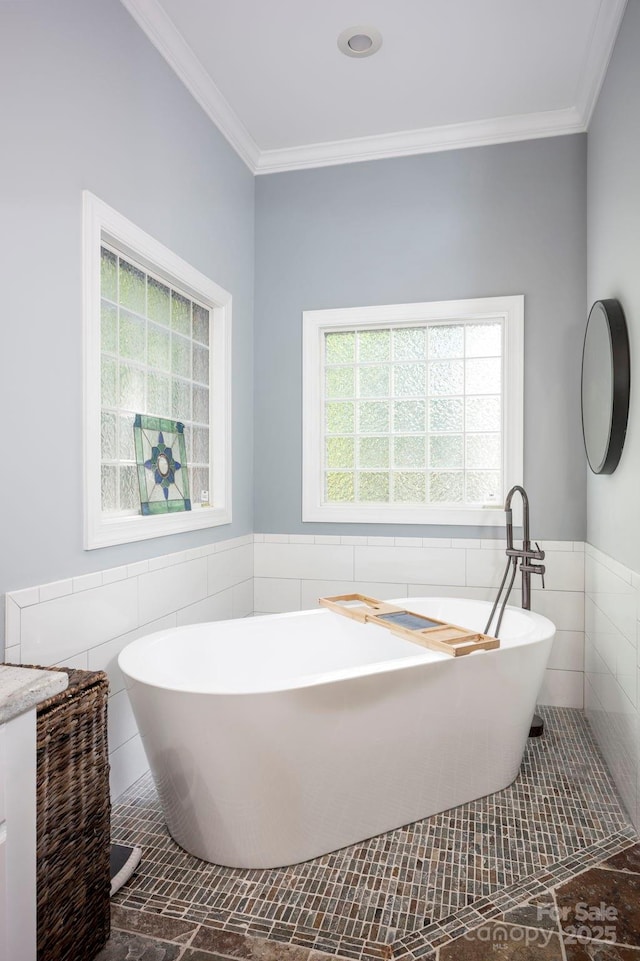 full bathroom featuring tile walls, wainscoting, a freestanding tub, and crown molding