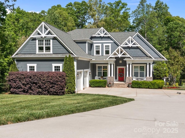 craftsman inspired home with a shingled roof, an attached garage, concrete driveway, and a front lawn