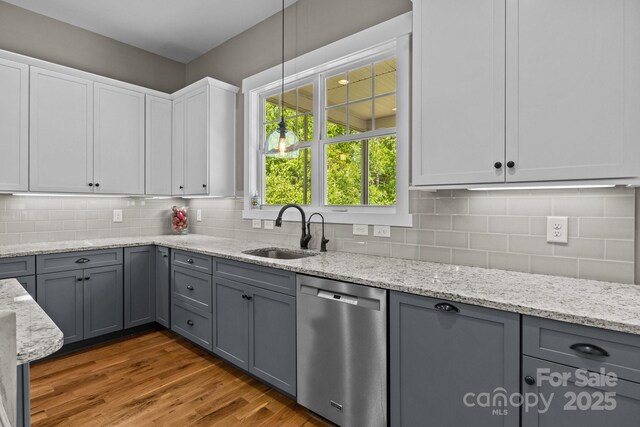 kitchen with stainless steel dishwasher, gray cabinets, and a sink