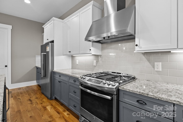 kitchen featuring gray cabinets, appliances with stainless steel finishes, white cabinets, and wall chimney range hood