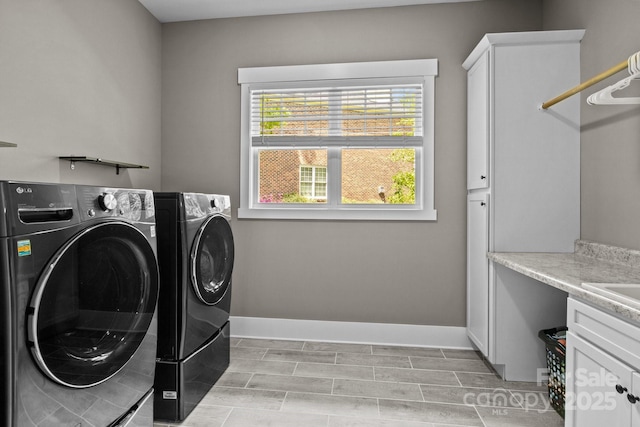 clothes washing area with baseboards, cabinet space, and washing machine and dryer