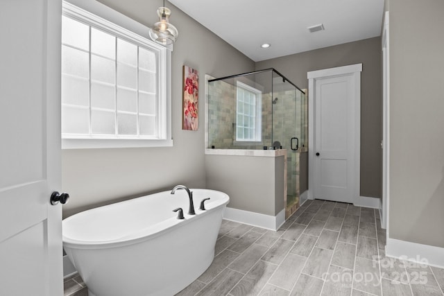 full bathroom featuring wood tiled floor, visible vents, a freestanding bath, a shower stall, and baseboards