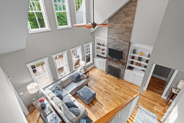 living area with built in features, a towering ceiling, and wood finished floors